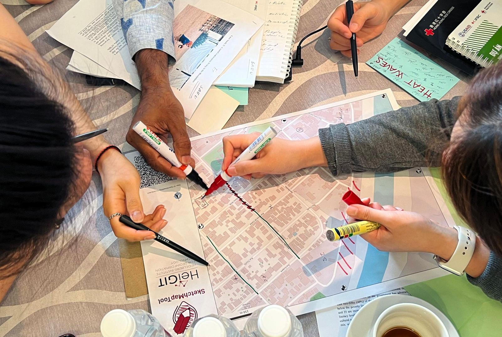 A group of people drawing on physical maps with markers