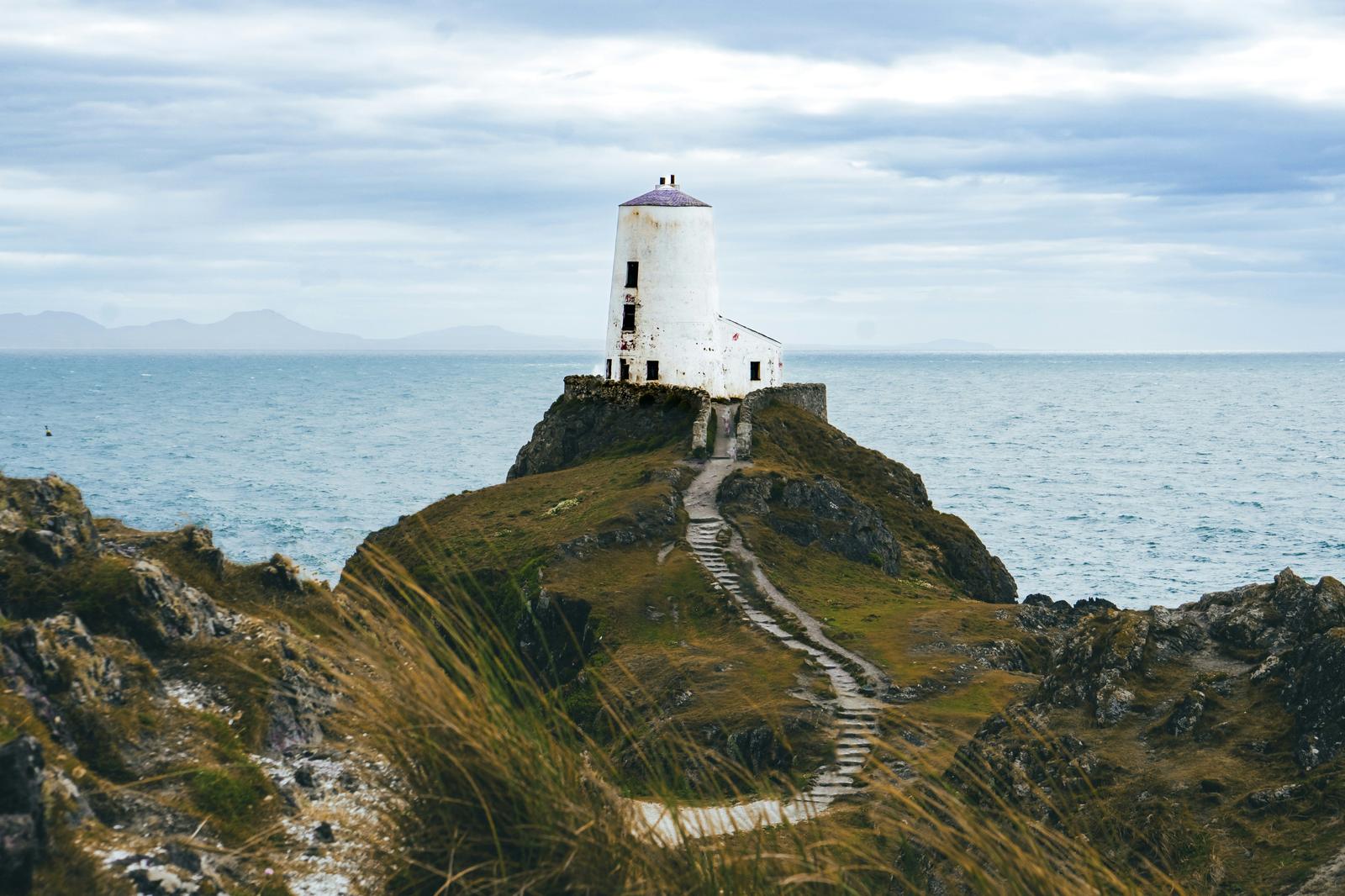 A lighthouse on a rocky cliff with a stepped path leading to it